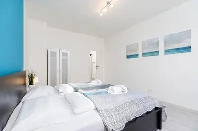 a white bedroom with a bed with white sheets and pillows at Apartments Cracow Rakowicka by Noclegi Renters in Kraków