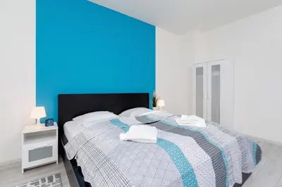 a bedroom with a bed with a blue wall at Apartments Cracow Rakowicka by Noclegi Renters in Kraków