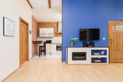 a living room with a blue wall and a tv at Deluxe Apartments Kraków Brzozowa by Noclegi Renters in Kraków