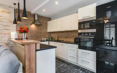 a kitchen with white cabinets and black appliances at Deluxe Apartments Kraków Brzozowa by Noclegi Renters in Kraków
