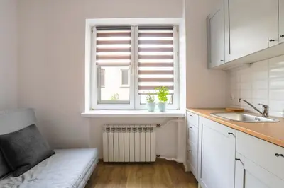a kitchen with white cabinets and a window with a radiator at Apartament Pod Winogronami in Kraków