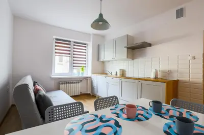 a living room with a table and a kitchen at Apartament Pod Winogronami in Kraków