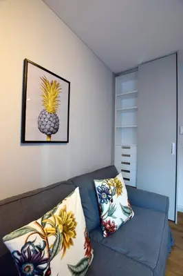 a living room with a couch and a pineapple picture on the wall at Jewish Quarter Small Apartment in Kraków