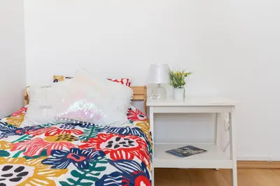 a bed with a white nightstand next to a white table at ap4you Tauron Cracow in Kraków