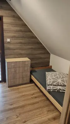 a bedroom with a bed and a wooden wall at Domek Nad Brzegiem in Witanowice