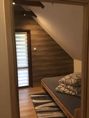 a room with a bed and a staircase with wooden walls at Domek Nad Brzegiem in Witanowice