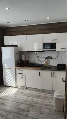 a kitchen with white cabinets and white appliances at Domek Nad Brzegiem in Witanowice