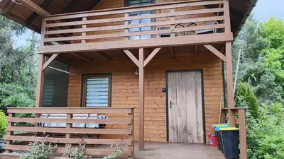 a wooden cabin with a deck and a door at Domek Nad Brzegiem in Witanowice