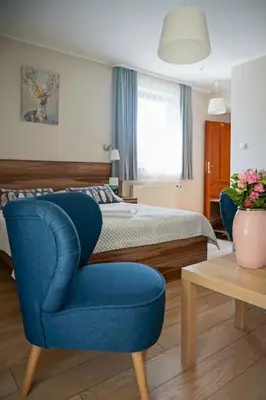 a bedroom with a blue chair and a bed at Hotel Victoria in Olkusz