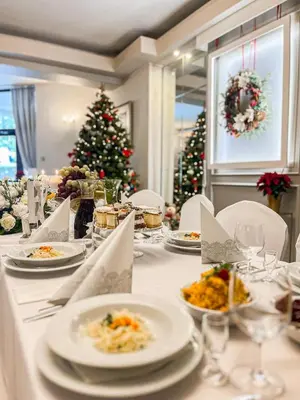 a table with plates of food and a christmas tree at Hotel Victoria in Olkusz