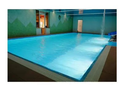 a large swimming pool with blue water in a room at Wyspa Mszanka in Mszana Dolna