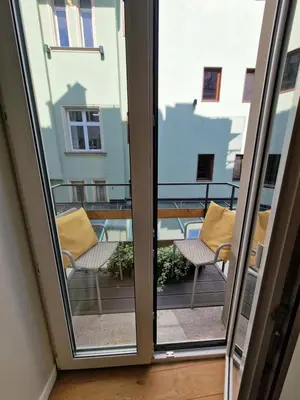 a sliding glass door with two chairs on a balcony at Avanti Palazzo in Kraków