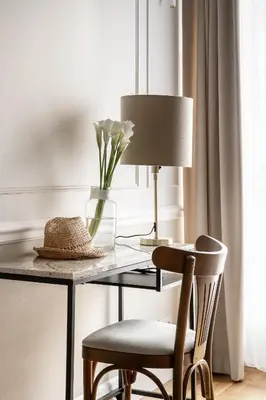 a desk with a lamp and a chair with a vase of flowers at Avanti Palazzo in Kraków