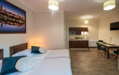 a bedroom with two beds and a desk and a kitchen at Apartments 17 Szewska in Kraków