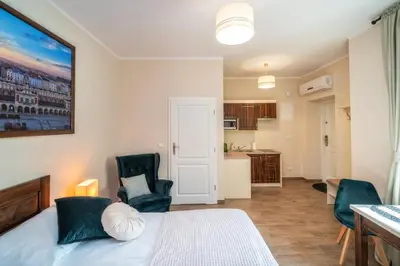 a bedroom with a bed and two chairs and a kitchen at Apartments 17 Szewska in Kraków