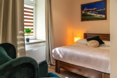 a bedroom with a bed and a chair and a window at Apartments 17 Szewska in Kraków