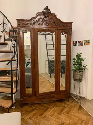 a wooden cabinet with a mirror in a living room at Charming studio apartment in the heart of the Jewish District! in Kraków