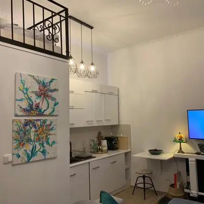a kitchen with white cabinets and a desk with a computer at Charming studio apartment in the heart of the Jewish District! in Kraków