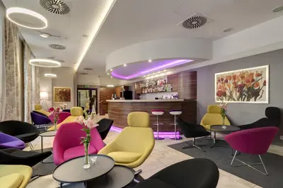 a waiting room with colorful chairs and tables at Golden Tulip Krakow City Center in Kraków