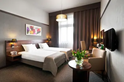 a hotel room with a bed and a chair at Golden Tulip Krakow City Center in Kraków