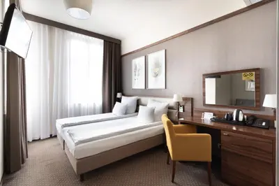 a hotel room with a large bed and a desk at Golden Tulip Krakow City Center in Kraków