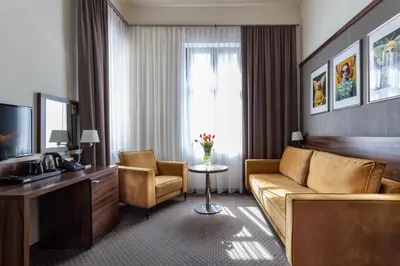 a hotel room with a couch and a desk and a window at Golden Tulip Krakow City Center in Kraków