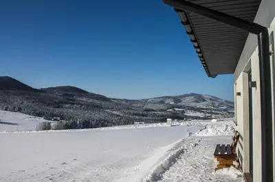 a bench sitting on top of a snow covered field at Domek POD GOLCOWEM in Limanowa