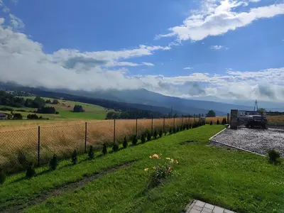a fence in a field with mountains in the background at Domek POD GOLCOWEM in Limanowa