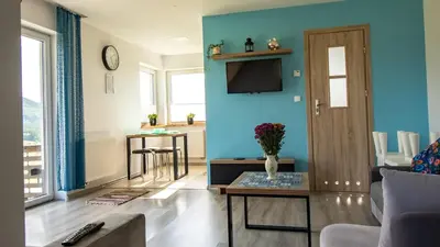 a living room with a blue wall and a tv at Domek POD GOLCOWEM in Limanowa
