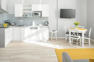 a kitchen with white cabinets and a table at MY KRAKOW Apartments - Topolowa 8 in Kraków