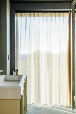 a bathroom with a window with a white curtain at PURO Kraków Stare Miasto in Kraków