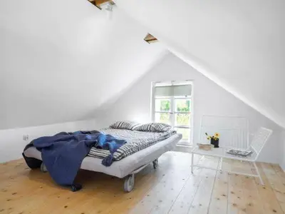 a white bedroom with a bed and a table at Chatka w trawach in Kraków