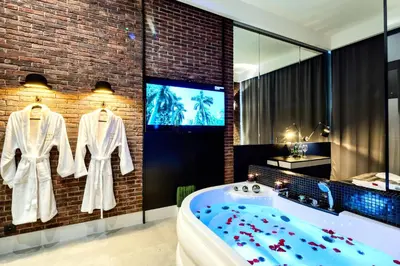 a bathroom with a bath tub and a tv at Starowiślna VIP Apartamenty JACUZZI in Kraków
