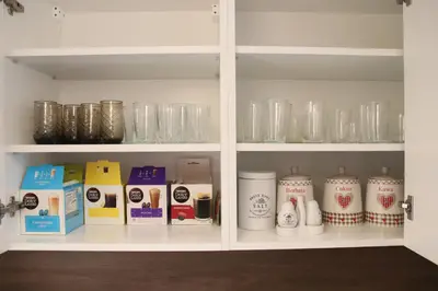 a white cabinet filled with lots of glass jars at Róża Pustyni in Chrzanów