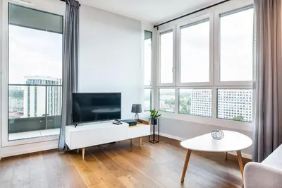 a living room with a tv and large windows at InPoint Mogilska Tower City View Apartments near Tauron Arena Self Check-in in Kraków