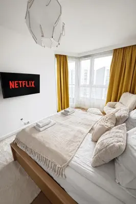 a bedroom with a large bed with a netflix sign on the wall at InPoint Mogilska Tower City View Apartments near Tauron Arena Self Check-in in Kraków
