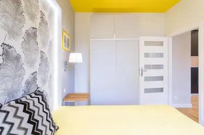a bedroom with a bed with a yellow ceiling at Apartament przy Parku Krakowskim in Kraków