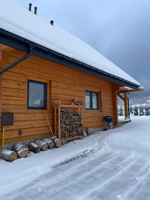a log cabin in the snow with a pile of wood at Miętusowa Chata pod Babią in Zawoja