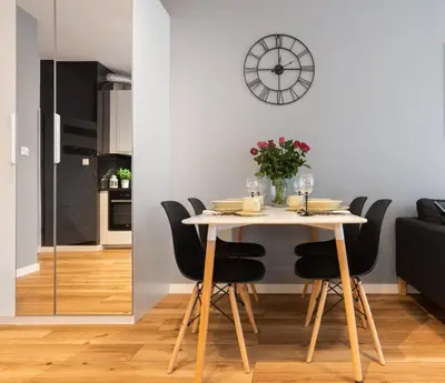 a dining room table with black chairs and a clock on the wall at NOVUM Apartment with Parking in Kraków
