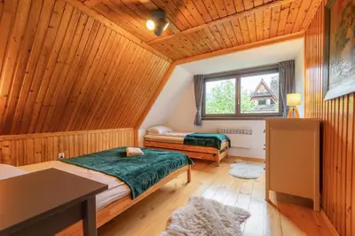 a bedroom with two beds in a wooden cabin at Willa Lavinka z sauną in Zawoja