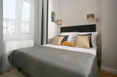 a bedroom with a bed with pillows and a window at Gem Apartment by Castle (Old Town Krakow) in Kraków