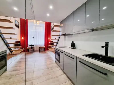 a kitchen with white cabinets and a red curtain at LOFT-to-be Apartment in Kraków