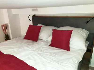 a white bed with two red pillows on it at LOFT-to-be Apartment in Kraków