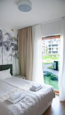 a bedroom with a bed and a large window at NEARTOpl Rakowicka apartments Parking in Kraków