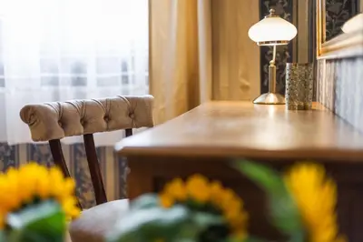 a desk with a chair next to a table with flowers at Vintage Senacka 5 Apartments in Kraków