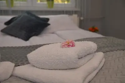 a white towel with a flower on top of a bed at Apartament Skałka in Jaworzno