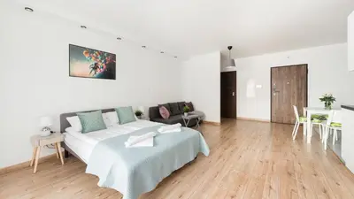 a white bedroom with a large bed and a table at Wiślane Tarasy, Sun & Snow in Kraków