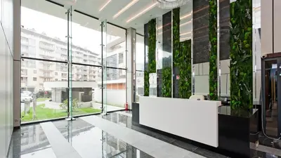 an office lobby with a white reception desk and plants on the walls at Wiślane Tarasy, Sun & Snow in Kraków
