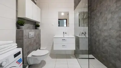 a white bathroom with a toilet and a sink at Wiślane Tarasy, Sun & Snow in Kraków