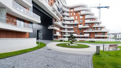 a large apartment building with a tree in a courtyard at Wiślane Tarasy, Sun & Snow in Kraków